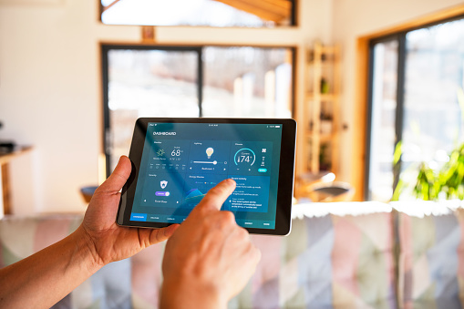 Unrecognisable man using tablet with smart home control functions at home.